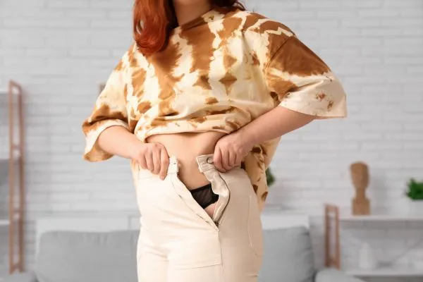 Image of woman trying to do her trousers up after pregnancy weight gain Burnley